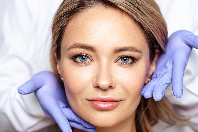 Woman receiving facial examination by dentist wearing purple gloves in clinical setting.