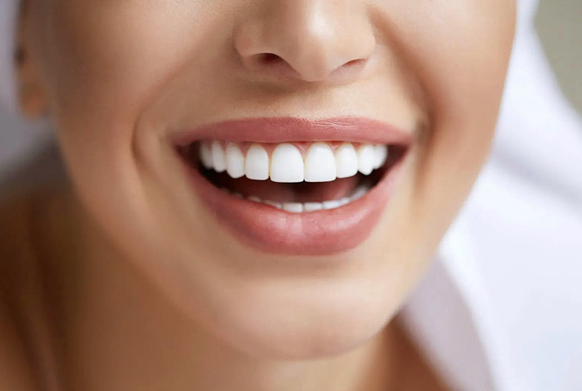 Close-up of woman's bright, white smile showing healthy teeth and gums indoors.